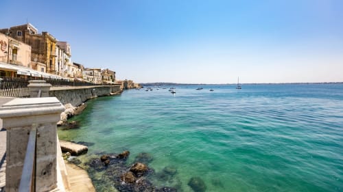 Maryam 23 waterfront view in Siracusa with turquoise Mediterranean waters and historic seaside buildings