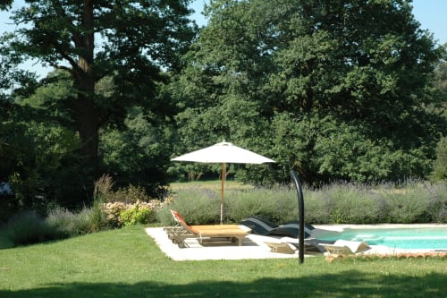 Espace piscine du gîte de luxe Le Lapin sur le Toit avec transats, parasol blanc et jardins luxuriants à Rouffignac, France