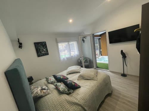 Chambre moderne au Gîte du Miroir à Domérat : lit, télévision, portes sur jardin et décoration contemporaine