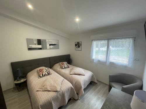 Chambre twin lumineuse au Gîte du Miroir Domérat en France, équipée d'aménagements modernes et vue sur le jardin