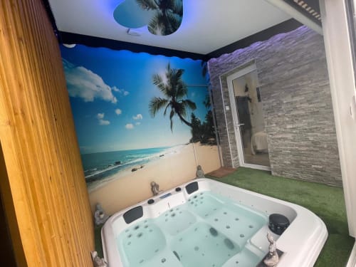 Luxueux bain à remous au Gîte du Miroir Domérat avec fresque murale plage, idéal pour la détente