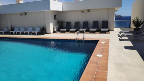 Terraza de piscina de El Faro de los Genoveses con agua turquesa, tumbonas y vistas al mar de Almería