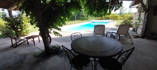Shaded patio with wrought iron dining table and pool view at Les Gites de Campardon, Monties, France