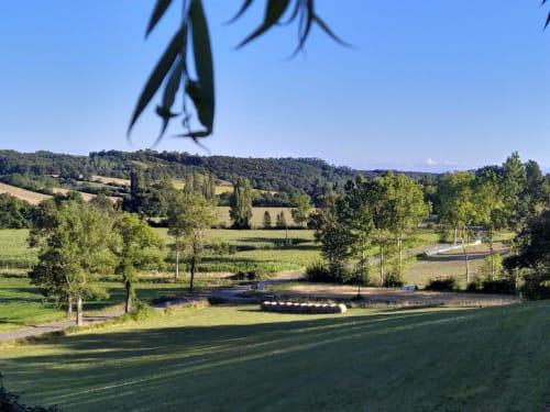 Scenic rural landscape at Les Gites de Campardon in Monties, France with green fields, trees, and a small waterway