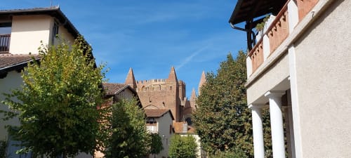 Medieval brick tower and stone buildings at Les Gites de Campardon in Monties, France, with ivy-covered walls under blue sky