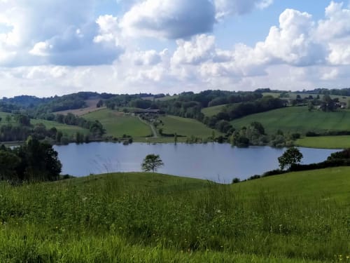 Rolling green hills and lake view near Les Gites de Campardon in Monties, France