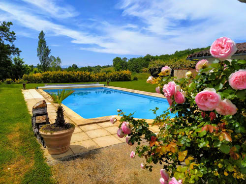 Pink roses frame a sparkling blue swimming pool at Les Gites de Campardon, a French countryside bed and breakfast in Monties