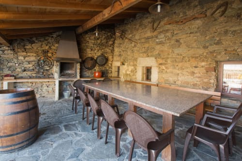 Rústico comedor de piedra con vigas de madera, mesa larga y chimenea en la casa rural El Horno de Rinconada en Ávila, España