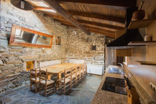 Cocina y comedor rústico con vigas de madera, encimeras de granito y mesa de madera en casa rural de Ávila
