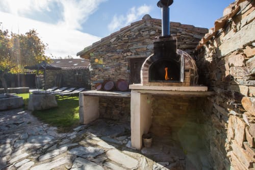 Tradicional horno de leña de piedra en la casa rural El Horno de Rinconada en Ávila, España, con llamas visibles en su interior