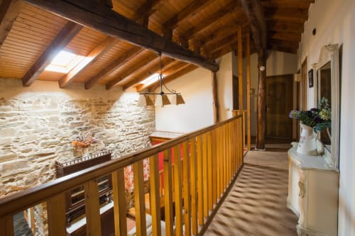 Pasillo de loft rústico con vigas de madera y muros de piedra en Apartamentos Turísticos Ávila, casa rural española