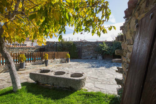 Patio histórico de piedra en la casa rural El Horno de Rinconada en Ávila, España, con antiguos elementos de piedra y árbol otoñal