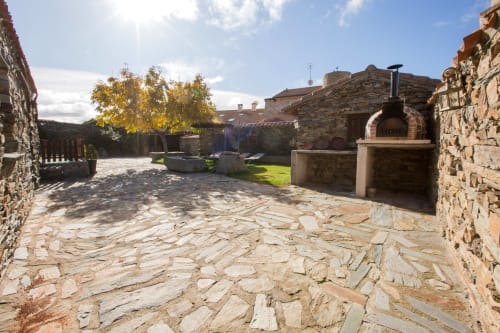 Patio de piedra con horno de leña en casa rural de Ávila, arquitectura tradicional y vistas a la montaña