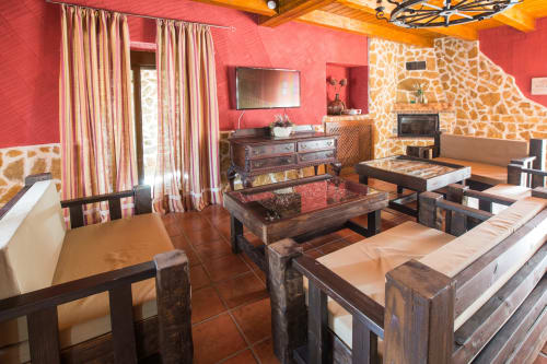 Amplia sala de estar con paredes rosa coral, detalles con patrón de jirafa, muebles de madera oscura y vistas a las montañas en Apartamentos