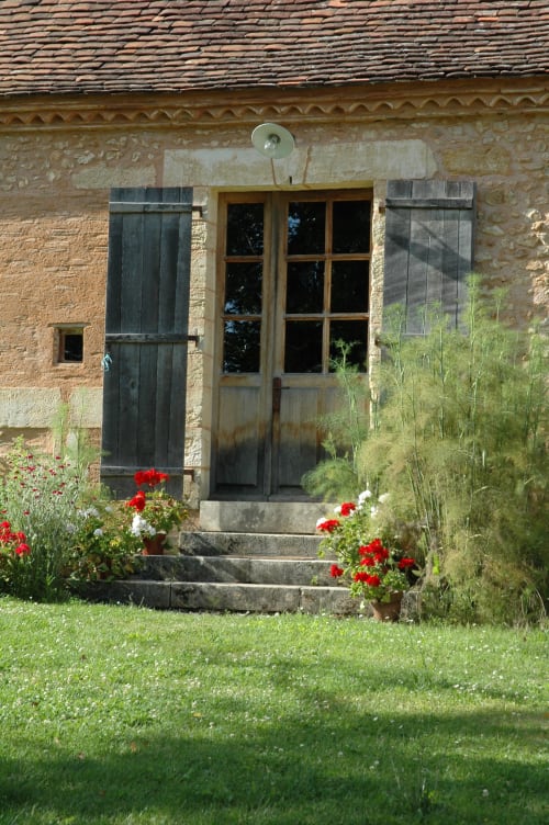 Entrée pittoresque du gîte en pierre Le Lapin sur le Toit avec fleurs rouges et portail de jardin à Rouffignac, France