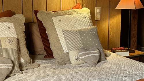 Chambre élégamment décorée au gîte Le Lapin sur le Toit à Rouffignac avec literie matelassée, coussins décoratifs et ambiance chaleureuse
