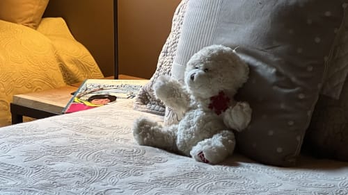 Ours en peluche blanc avec cœur rouge sur un lit douillet au Lapin sur le Toit, refuge champêtre cosy français
