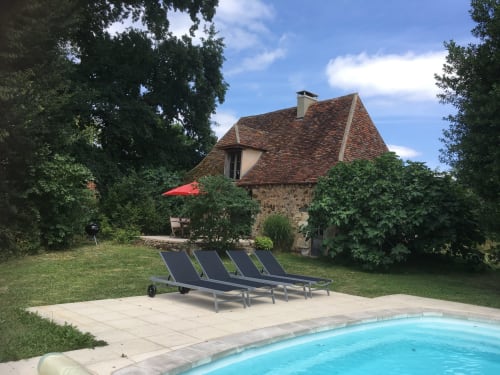 Maison en pierre avec piscine au gîte Le Lapin sur le Toit à Rouffignac, équipée de chaises longues et parasol rouge