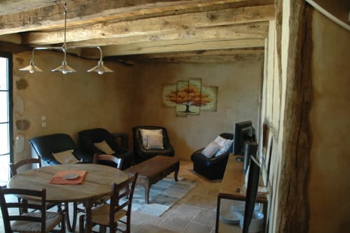 Salon rustique du Lapin sur le Toit avec poutres apparentes, chaises noires, table à manger et cheminée