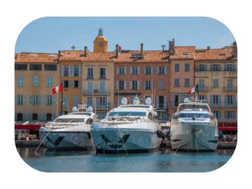 Yachts de luxe amarrés dans le port de La Croix Valmer avec des bâtiments méditerranéens colorés et drapeaux français
