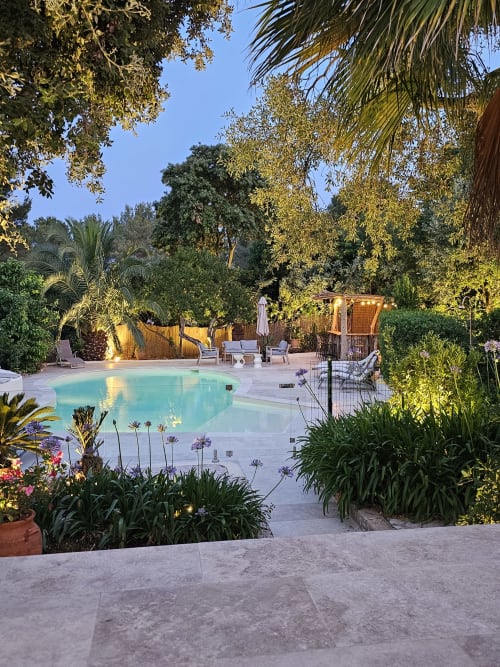 Vue crépusculaire de la piscine turquoise de la Villa Sigahi entourée de jardins luxuriants et de palmiers à La Croix Valmer