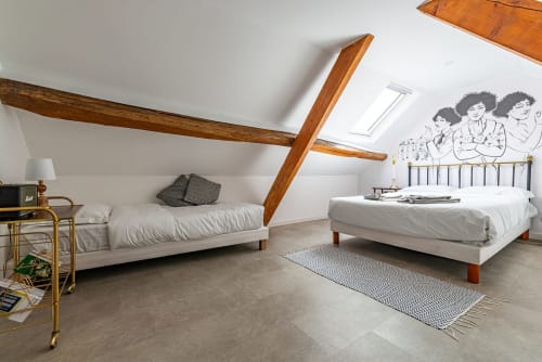 Bright attic bedroom at La Maison George with exposed wooden beams, two beds, white linens, and modern amenities in Flavigny