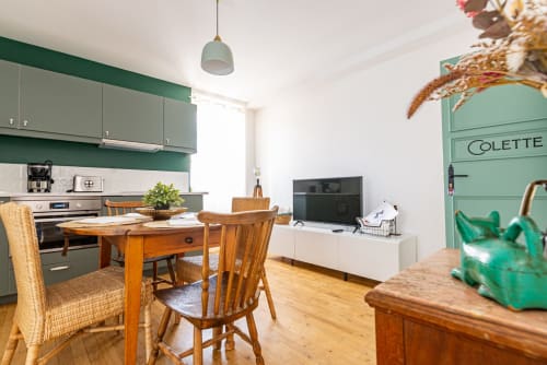 Modern kitchen-dining area in Logis Colette apartment at La Maison George with green cabinetry, wooden table, and integrated
