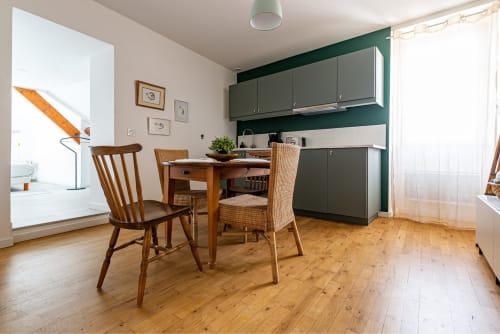 Logis Colette apartment at La Maison George features modern kitchen, wooden dining table with chairs, and hardwood floors in