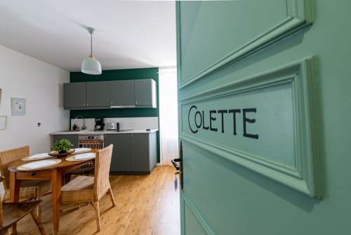 Colette apartment kitchen and dining area at La Maison George, Flavigny sur Ozerain, with green door, wood table, and modern