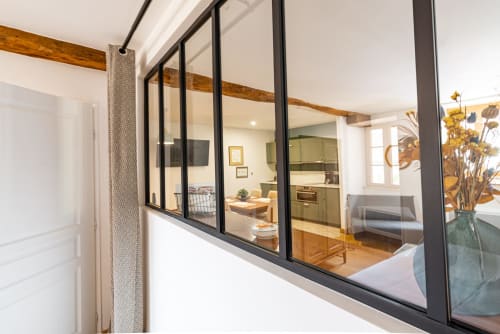 Modern glass partition viewing Logis George apartment at La Maison George with kitchen, dining area, and wooden beams
