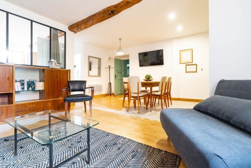 Modern apartment at La Maison George with dining table, gray sofa, wooden furniture, and open living space in Flavigny sur