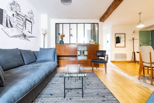 Modern living room in La Maison George's Logis apartment with blue sofa, wooden shelving, and dining area in Flavigny sur