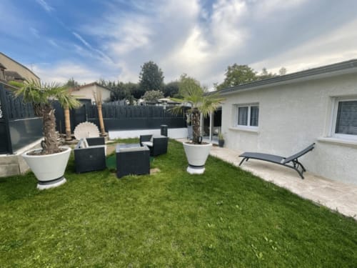 Jardin cottage moderne à Le Gîte du Miroir Domérat avec espace détente, palmiers et chaises longues blanches