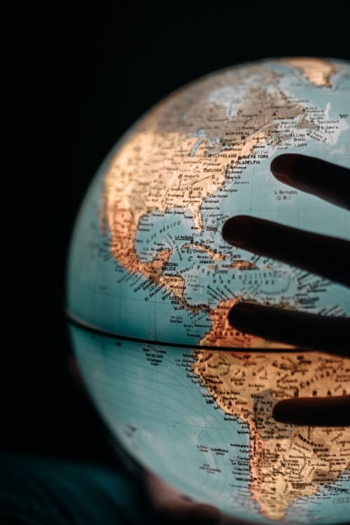 Mano che indica un globo con la mappa del Nord America mostrando città e paesi visibili