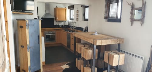 Cuisine moderne de l'appartement à Courchevel avec mobilier bois, îlot, plan de travail noir et tabourets rustiques