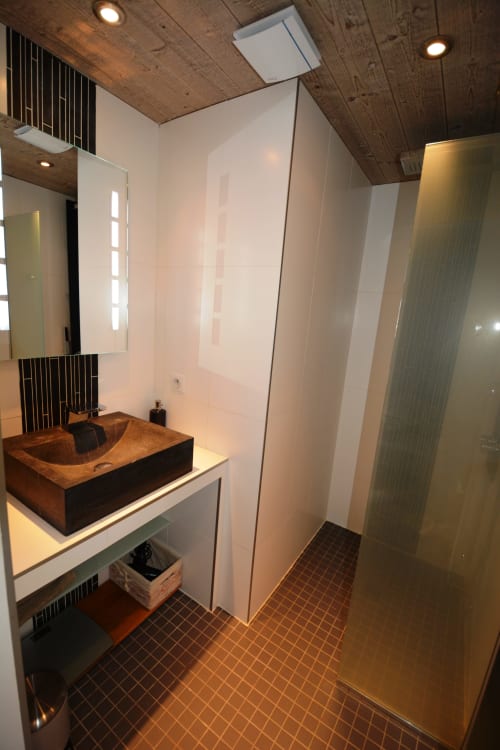 Salle de bain moderne et luxueuse à la Résidence Le Pacha Courchevel, avec vasque en bois, douche à l'italienne et design contemporain