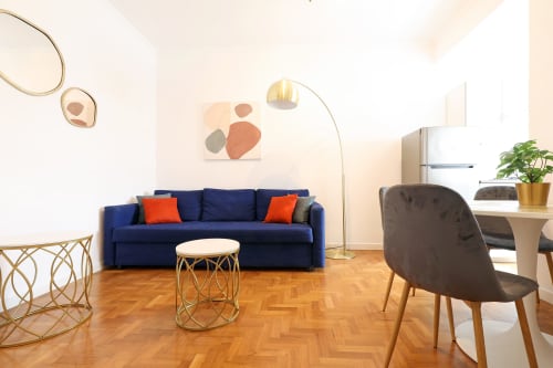 Elegante living room dell'hotel Re di Roma con divano blu navy, pavimento in legno e arredi contemporanei a Roma