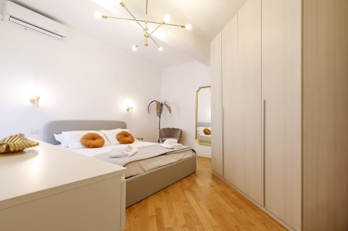 Camera moderna all'hotel Re di Roma a Roma con letto matrimoniale, dettagli dorati, pavimenti in legno e design minimalista