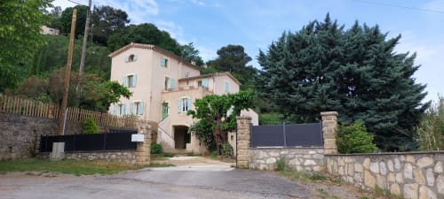 Le Mas de Trépeloup, gîte en Alès : villa en pierre couleur pêche avec lierre, portail d'entrée et cyprès élancés