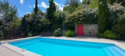 Piscine rectangulaire bleu vif au Mas de Trépeloup B&B à Alès, entourée de murs de pierre et de verdure méditerranéenne