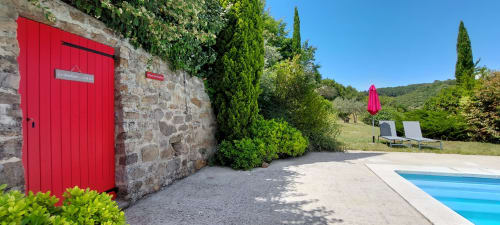 Le Mas de Trépeloup B&B à Alès avec sa porte d'entrée en pierre rouge vif, piscine et jardins luxuriants