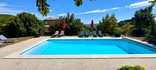 Piscine d'un bleu cristallin avec transats et parasols au Mas de Trépeloup, chambres d'hôtes en Provence près d'Alès