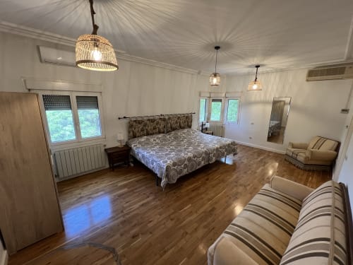 Espacioso dormitorio de villa de lujo con pisos de madera, cama queen, iluminación colgante y vistas a la montaña cerca del Puy du Fou