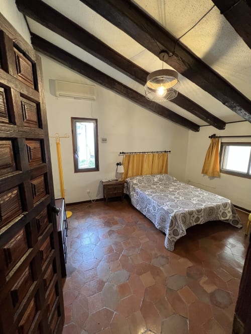 Dormitorio espacioso con vigas de madera vista, suelos de baldosas de terracotaVilla Luxury cerca de Puy du Fou