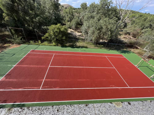 Cancha de tenis privada con superficies de juego roja y verde rodeada de árboles enVilla Luxury Tenis Junto A Puy Du Fou en Argés,