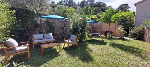 Espace lounge du jardin du Mas de Trépeloup avec mobilier en bois, parasols bleus et aménagements paysagers à Alès, France