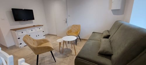 Salon moderne de l'appartement Gîte Bambou au Mas de Trépeloup, Alès, avec chaises moutarde, canapé gris, table basse blanche