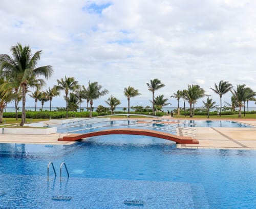 Piscina curva de lujo con vista al océano del Resort Mareazul, palmeras y playa en Playa del Carmen