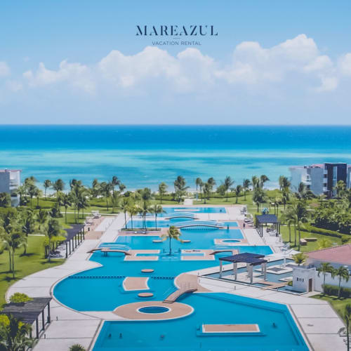 Complejo de piscinas del Resort Mareazul con aguas turquesas, palmeras y Mar Caribe en Playa del Carmen, México