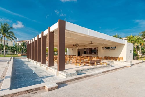 Punto Azul, bar frente al mar en Mareazul Resort, Playa del Carmen, con sillas de madera, columnas marrones y aguas tranquilas
